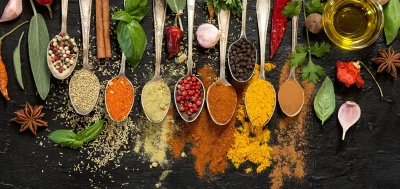 herbs and spices on spoons on a table.